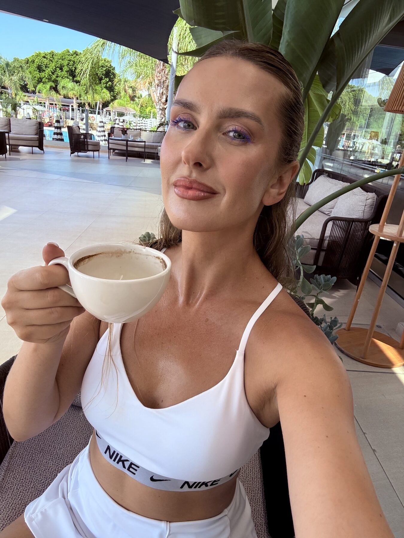 Malvina drinking coffee in white gym outfit